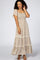Woman wearing a floral smocked maxi dress with flutter sleeves and tiered lace trim against a white background