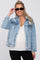 smiling woman wearing a distressed light wash denim jacket and black sunglasses over a white top