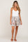 woman wearing white camisole and light blue tropical palm print shorts with tassel drawstring