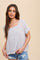 woman wearing a light grey short sleeve button up blouse with lace trim and denim shorts