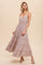 woman wearing a mauve tiered maxi dress with spaghetti straps and smocked waist against a beige background