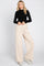 woman wearing black long sleeve turtleneck top and beige wide leg trousers with white sneakers