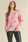 Woman wearing a light purple knit sweater with orange fuzzy star patterns and black leather pants