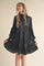 woman wearing a black long sleeve tiered dress with ruffle details and a mock neck