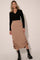 woman wearing a black long sleeve v-neck sweater and a beige midi skirt with gathered detailing, paired with black boots
