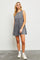 woman wearing a gray sleeveless denim dress with a flared hem and frayed edges