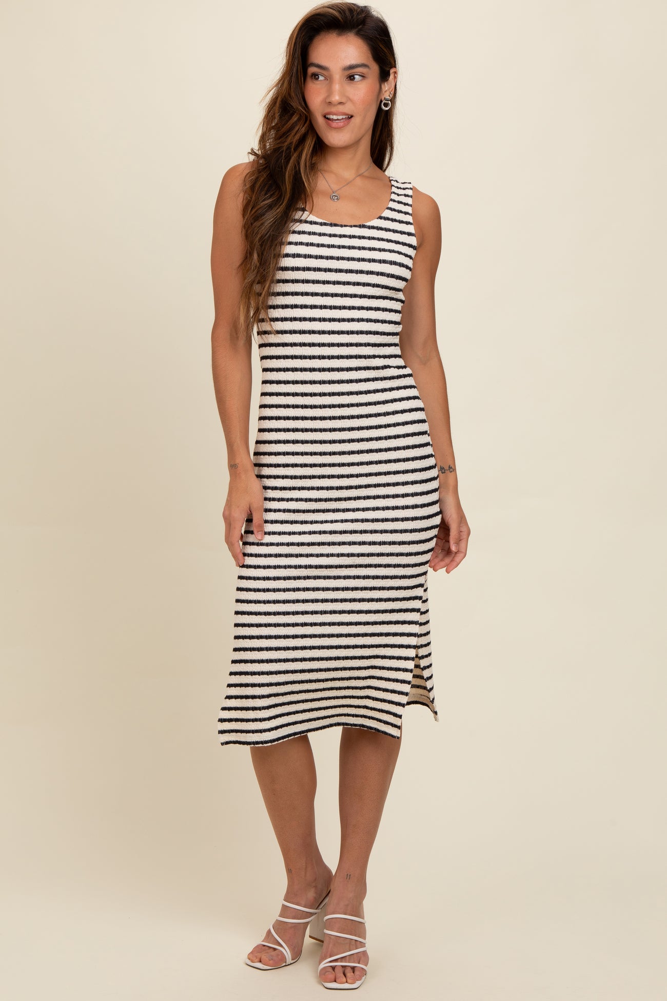 woman wearing a striped midi tank dress in black and cream with a fitted silhouette and a flared hem