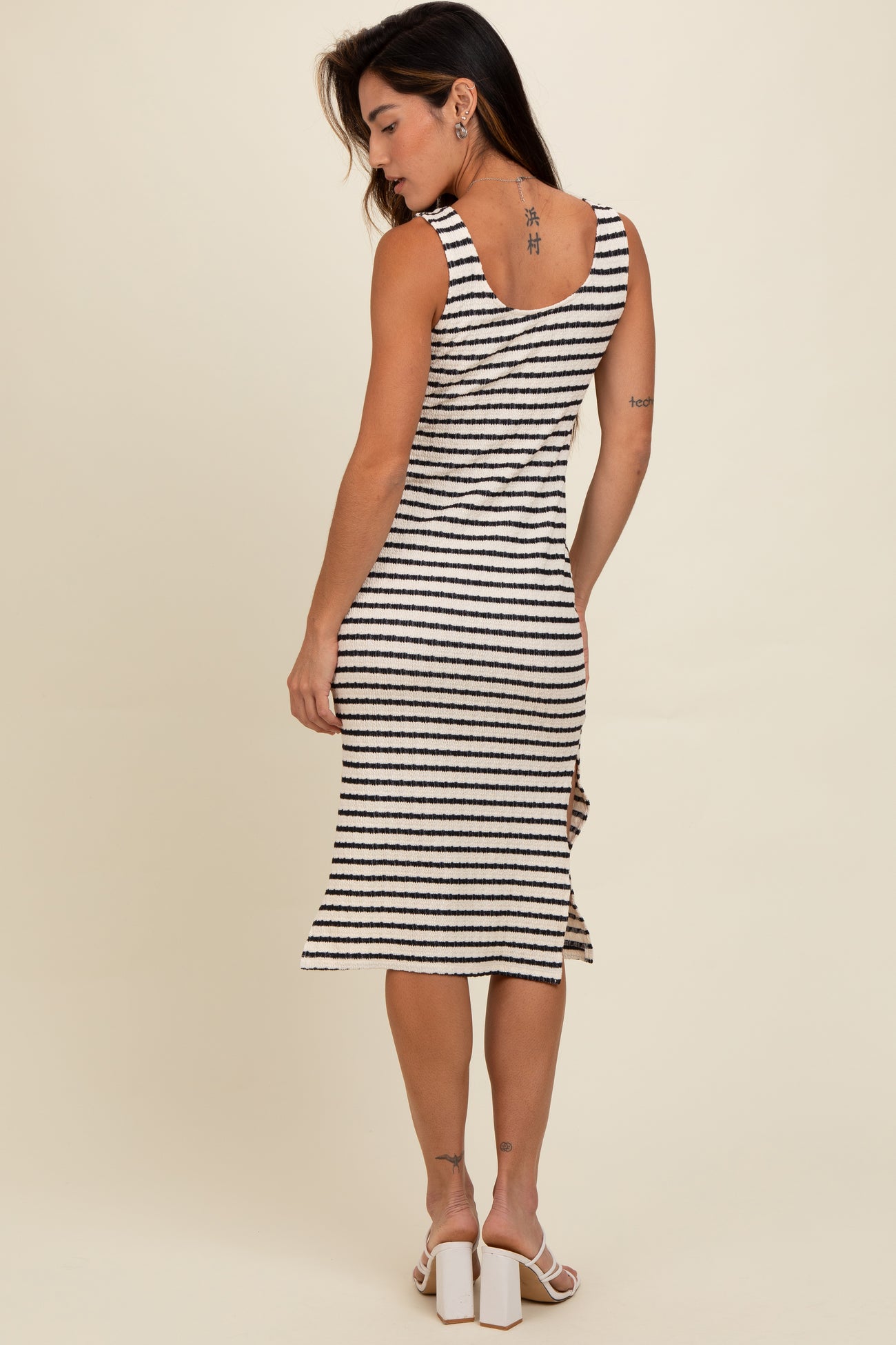 woman wearing a striped knee-length dress with a scoop back and fitted silhouette, shown from the back