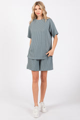 woman wearing a light blue striped short sleeve top and matching shorts with pockets, standing in white sneakers