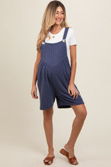 woman wearing a navy blue striped maternity romper with short legs and button details, showcasing her baby bump