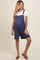 woman wearing a navy blue striped maternity romper with short legs and button details, showcasing her baby bump