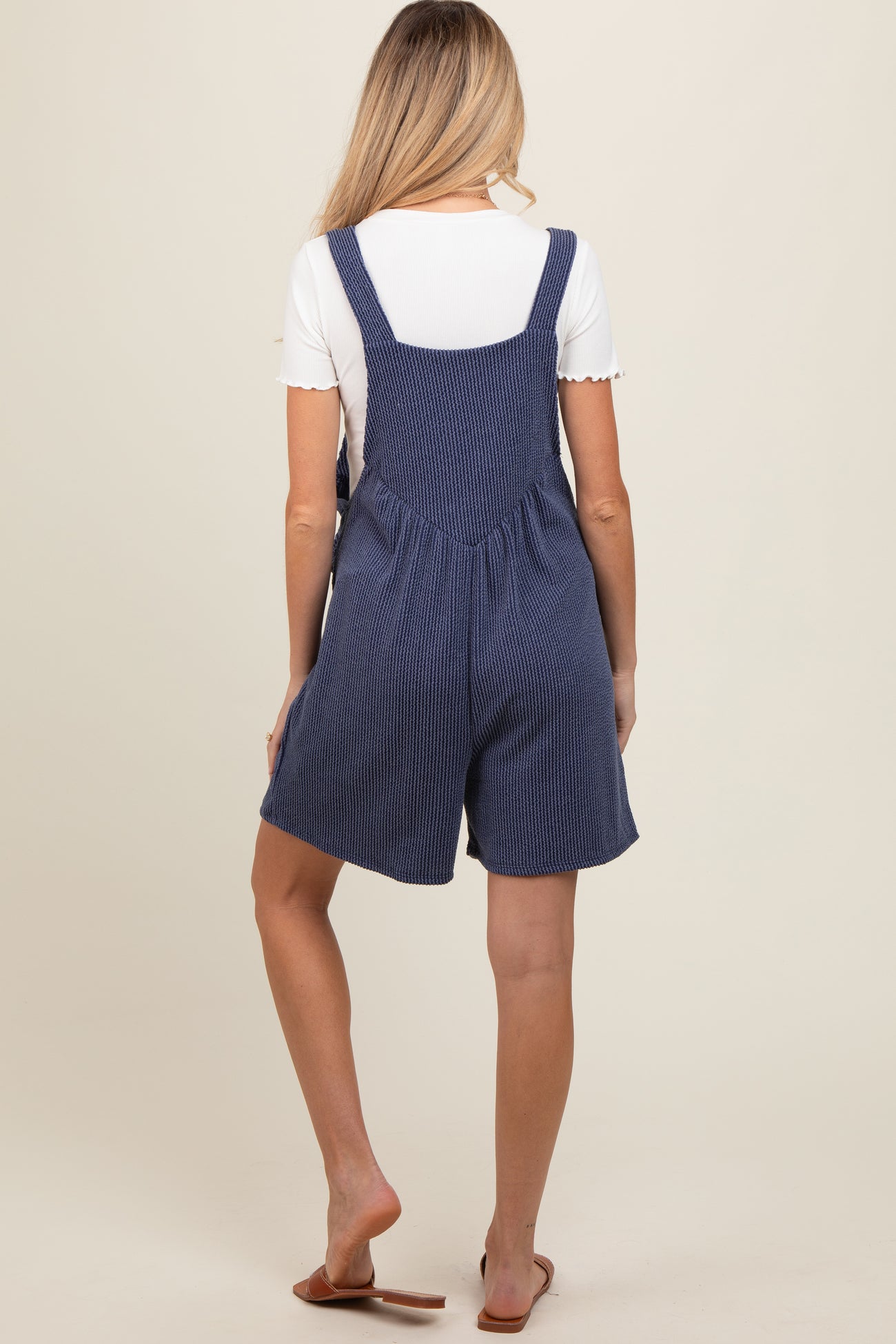 woman wearing a navy striped maternity romper with a relaxed fit and adjustable straps, showing a baby bump