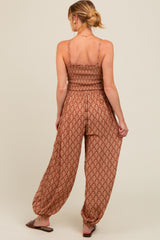 woman wearing a brown patterned maternity jumpsuit with a smocked bodice and relaxed fit pants from the back