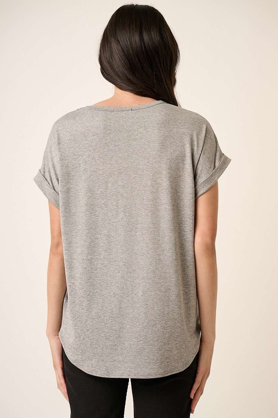 woman wearing a gray short sleeve top, viewed from the back, with rolled sleeves and a rounded hemline