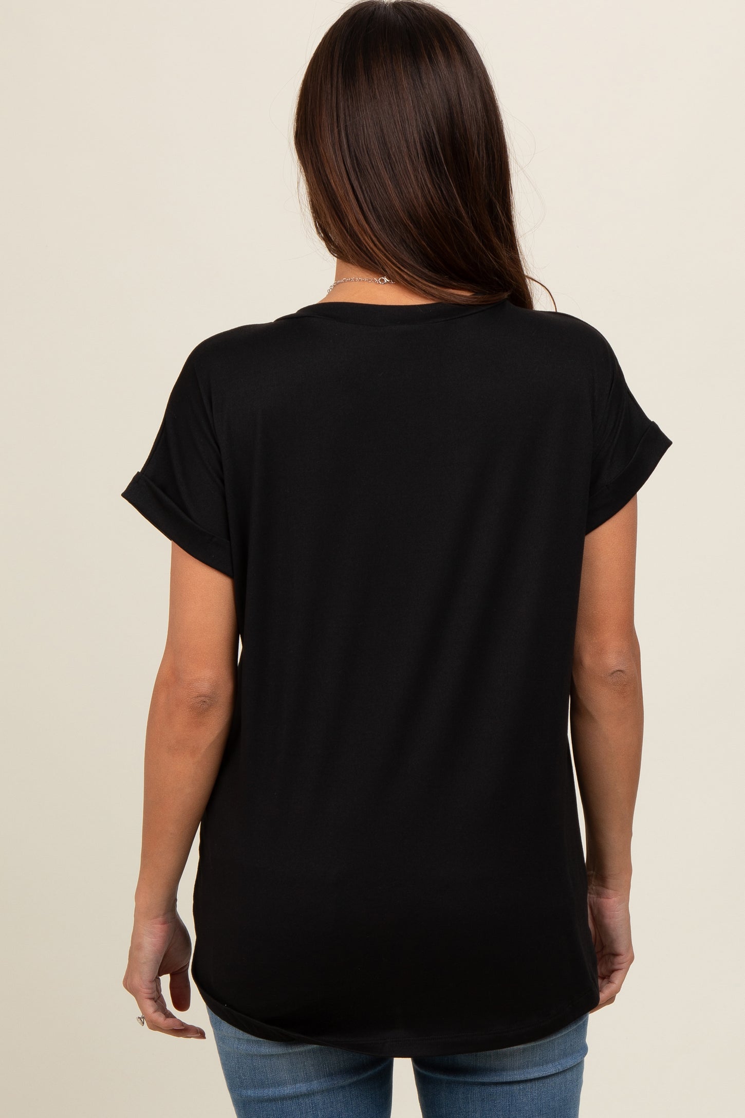 woman wearing a black short sleeve maternity top, viewed from the back, paired with light blue jeans
