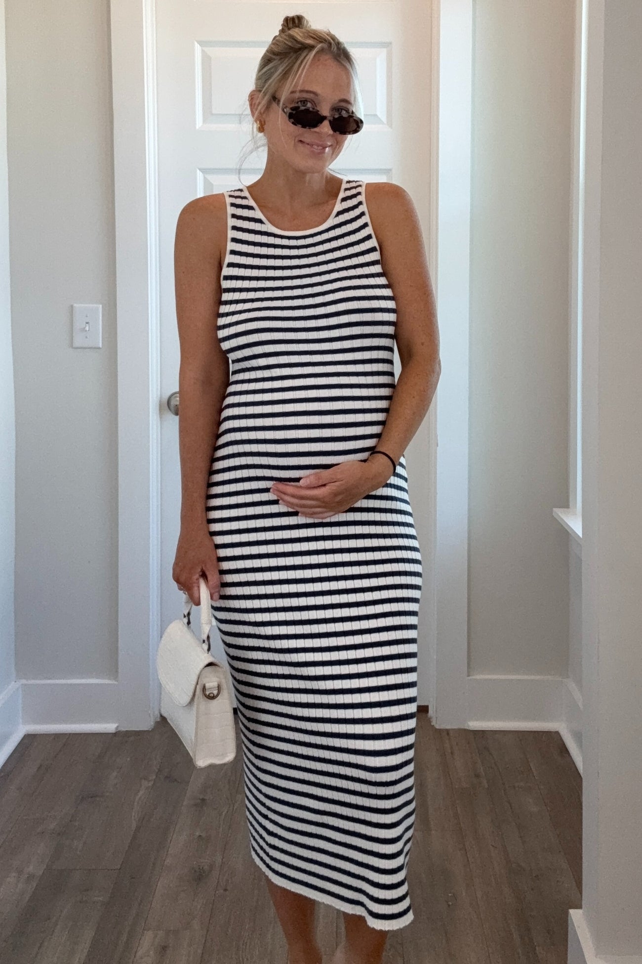woman wearing a black and white striped maternity dress and holding her baby bump