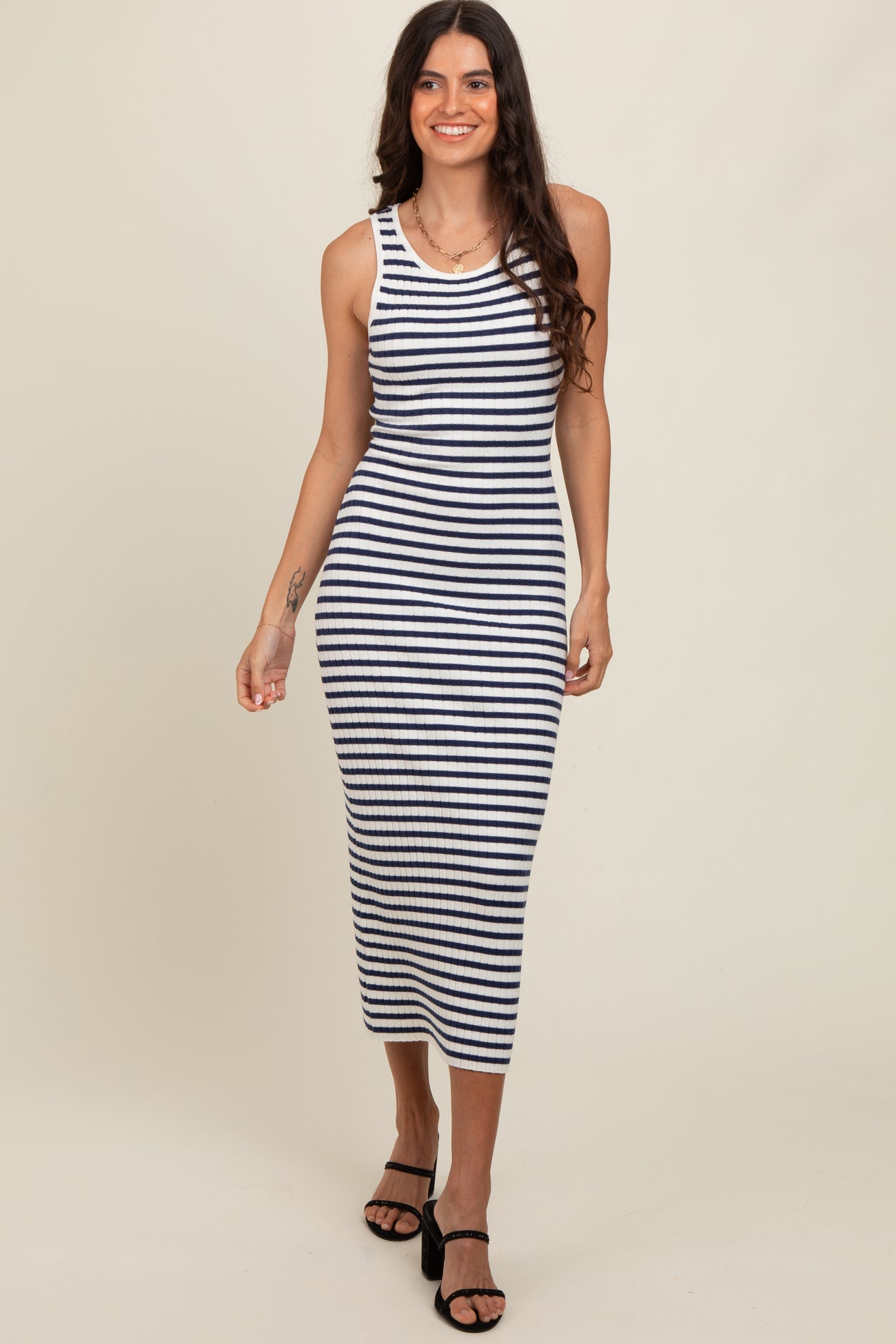 woman wearing a navy and white striped midi dress with a fitted silhouette and sleeveless design