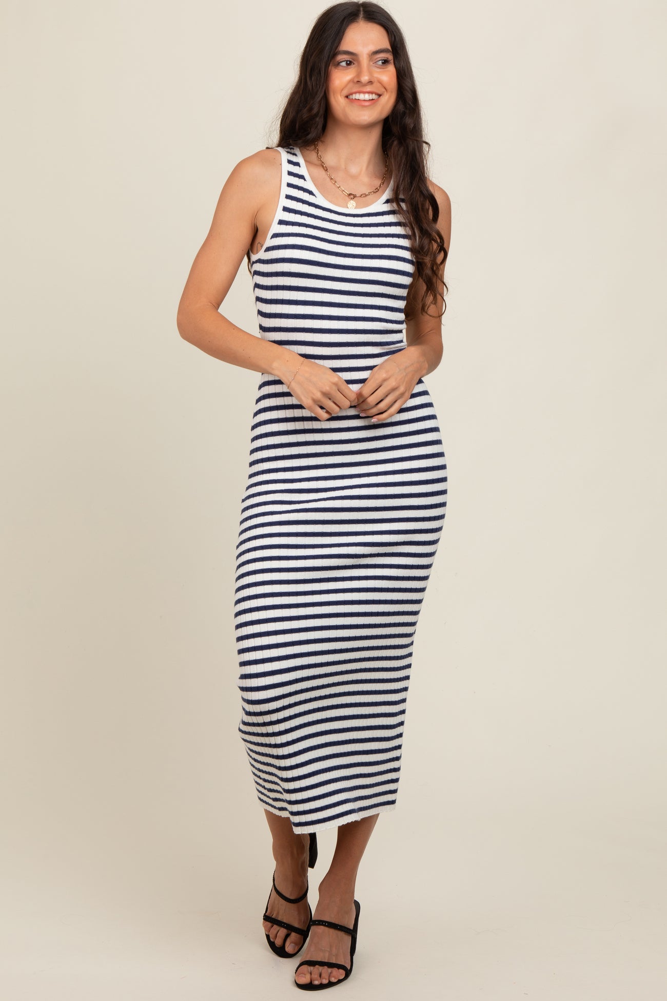 woman wearing a navy and white striped tank dress with a form-fitting silhouette and side slits