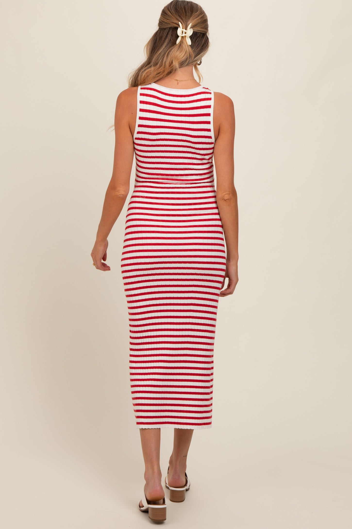 woman wearing a red and white striped maternity dress, showing a fitted style and mid-calf length from the back