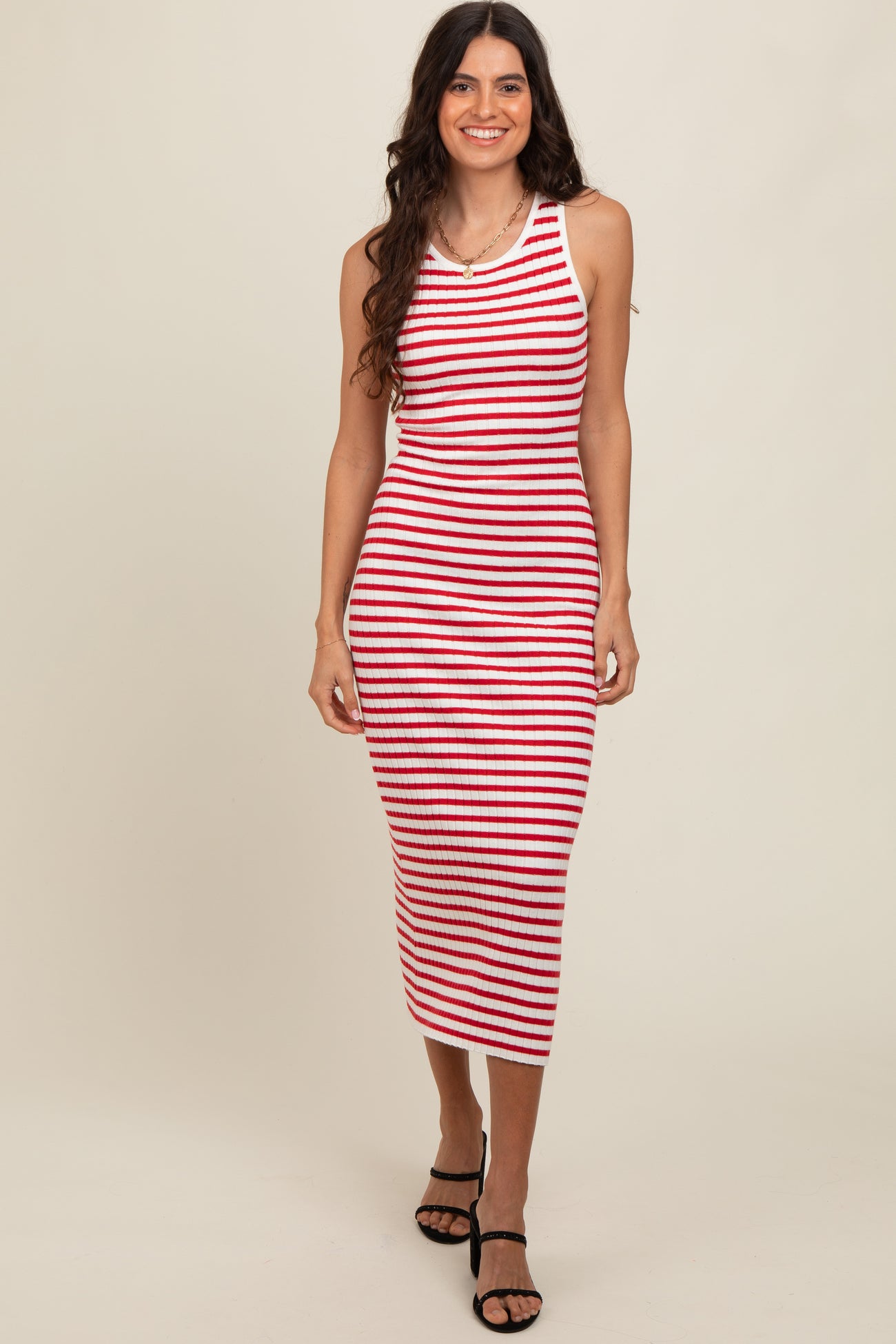 woman wearing a red and white striped sleeveless midi dress with a fitted silhouette and black strappy sandals