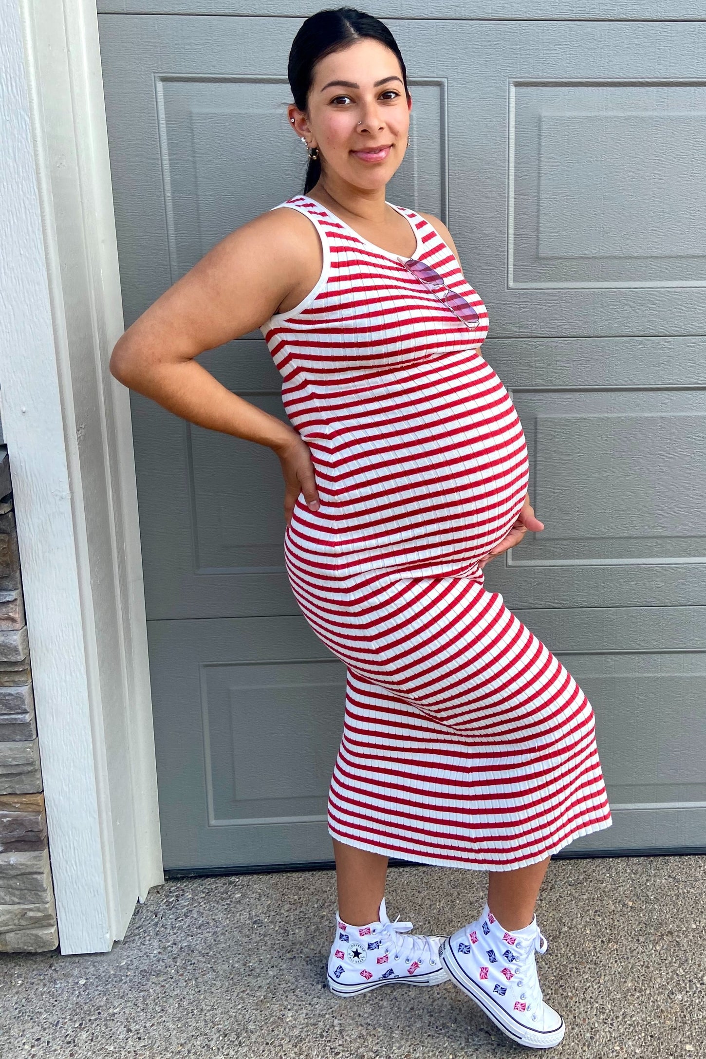 woman wearing a red and white striped maternity dress that shows her baby bump, paired with white sneakers