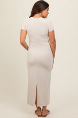 woman wearing a light beige maternity maxi dress with short sleeves and a back slit, showing her baby bump