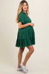 woman wearing a dark green short sleeve maternity dress with tiered ruffles and a visible baby bump