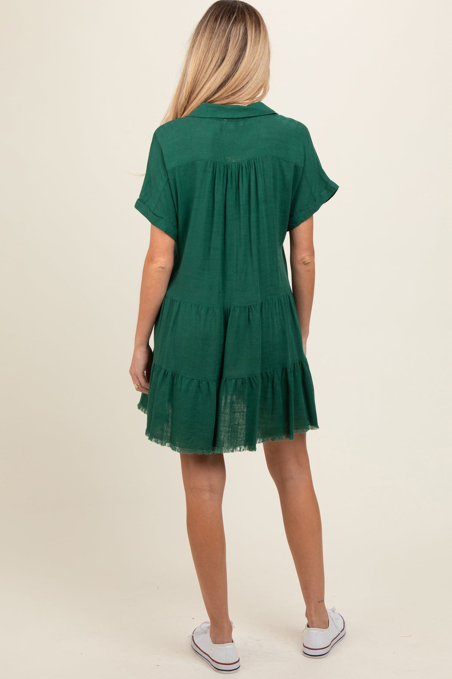 woman wearing a dark green short sleeve tiered maternity dress with a relaxed fit and a lightweight fabric