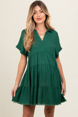 woman wearing a green short sleeve maternity dress with a tiered hem and v-neckline