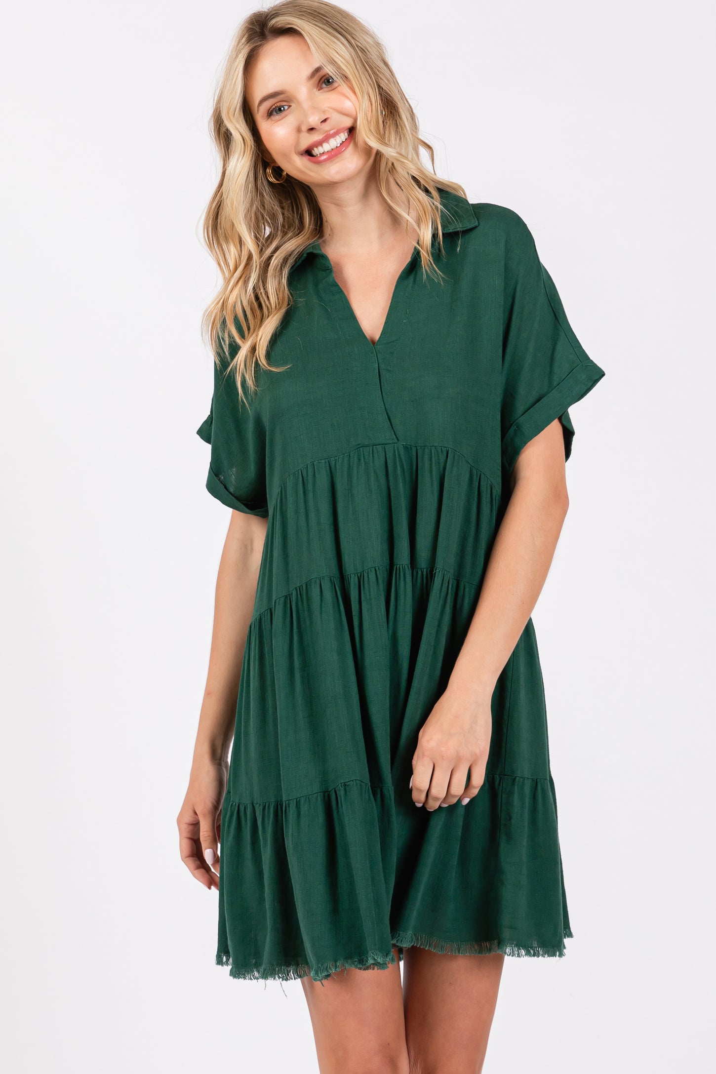woman wearing a green short sleeve tiered dress with a collared neckline and frayed hem