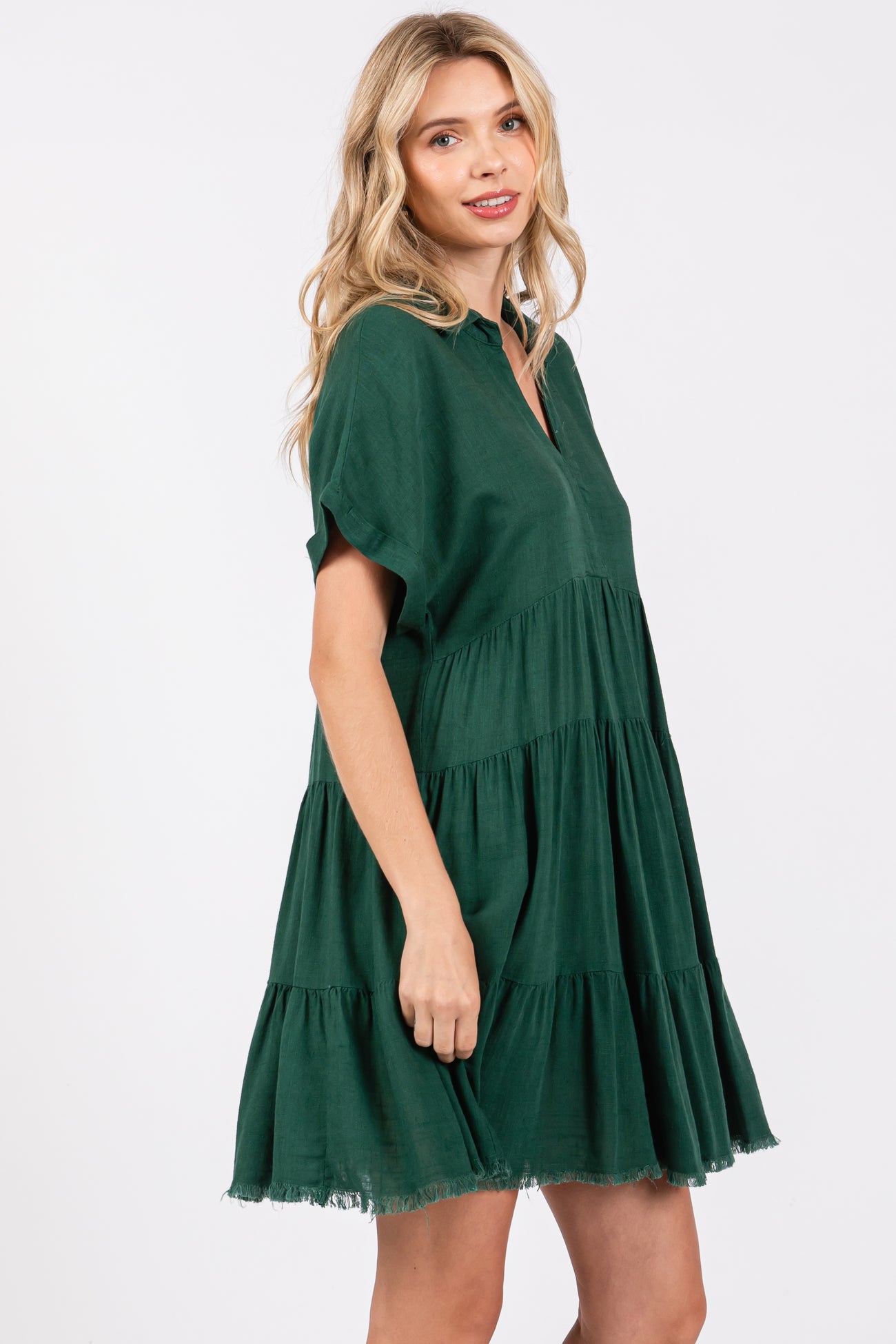 woman wearing a green tiered short dress with a collar and frayed hemline