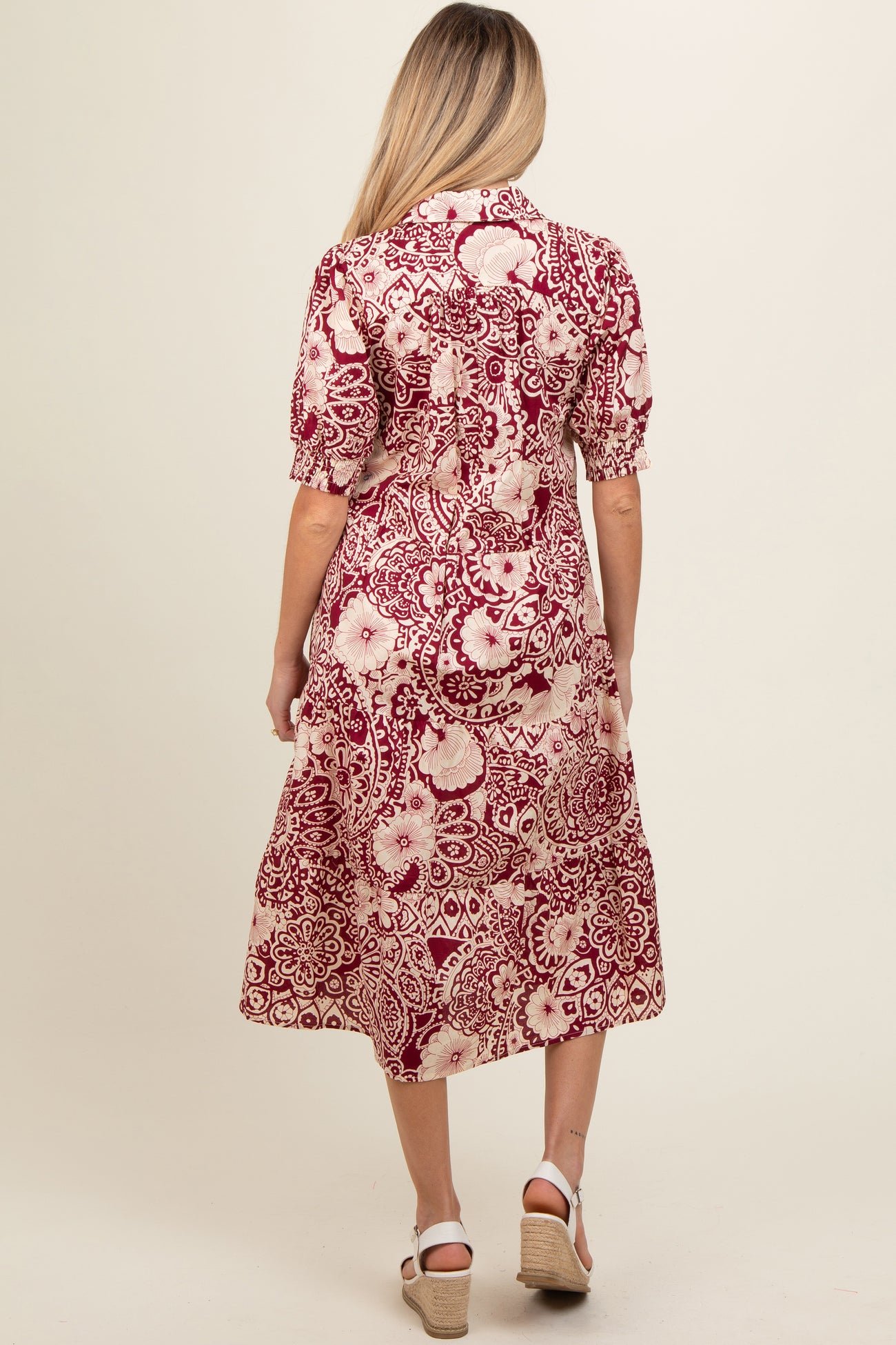 woman wearing a burgundy and cream floral print maternity dress with short sleeves and a midi length