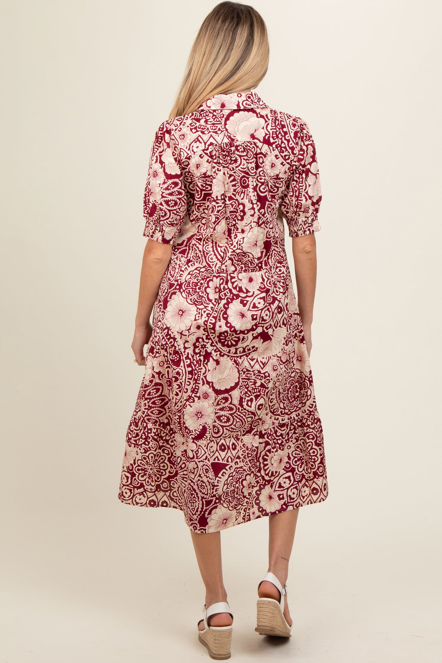 woman wearing a burgundy and cream floral print maternity dress with short sleeves and a midi length