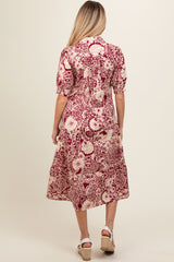 woman wearing a burgundy and cream floral print maternity dress with short sleeves and a midi length