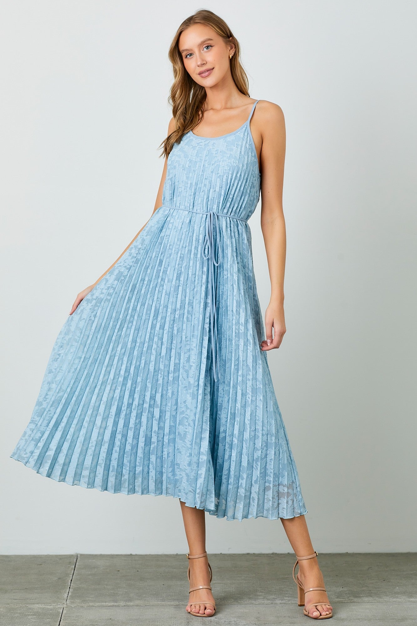 woman wearing a light blue pleated maxi dress with thin straps and a drawstring waist
