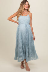 woman wearing a light blue pleated maternity dress with adjustable straps and a tied waist