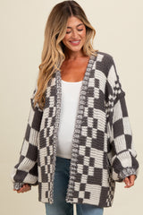 woman wearing a gray and white checkered oversized maternity cardigan with a visible baby bump