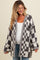 woman wearing a gray and white checkered oversized maternity cardigan with a visible baby bump
