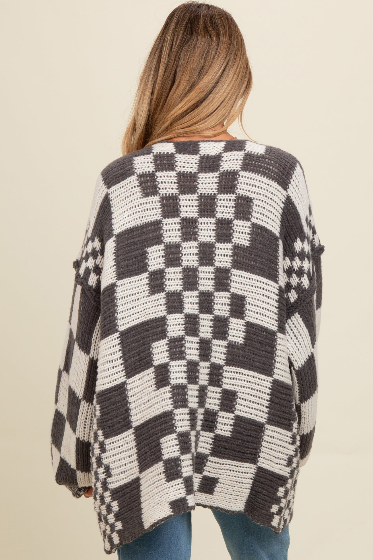 woman wearing a chunky oversized black and white checkered maternity cardigan, with a loose fit and dropped shoulders