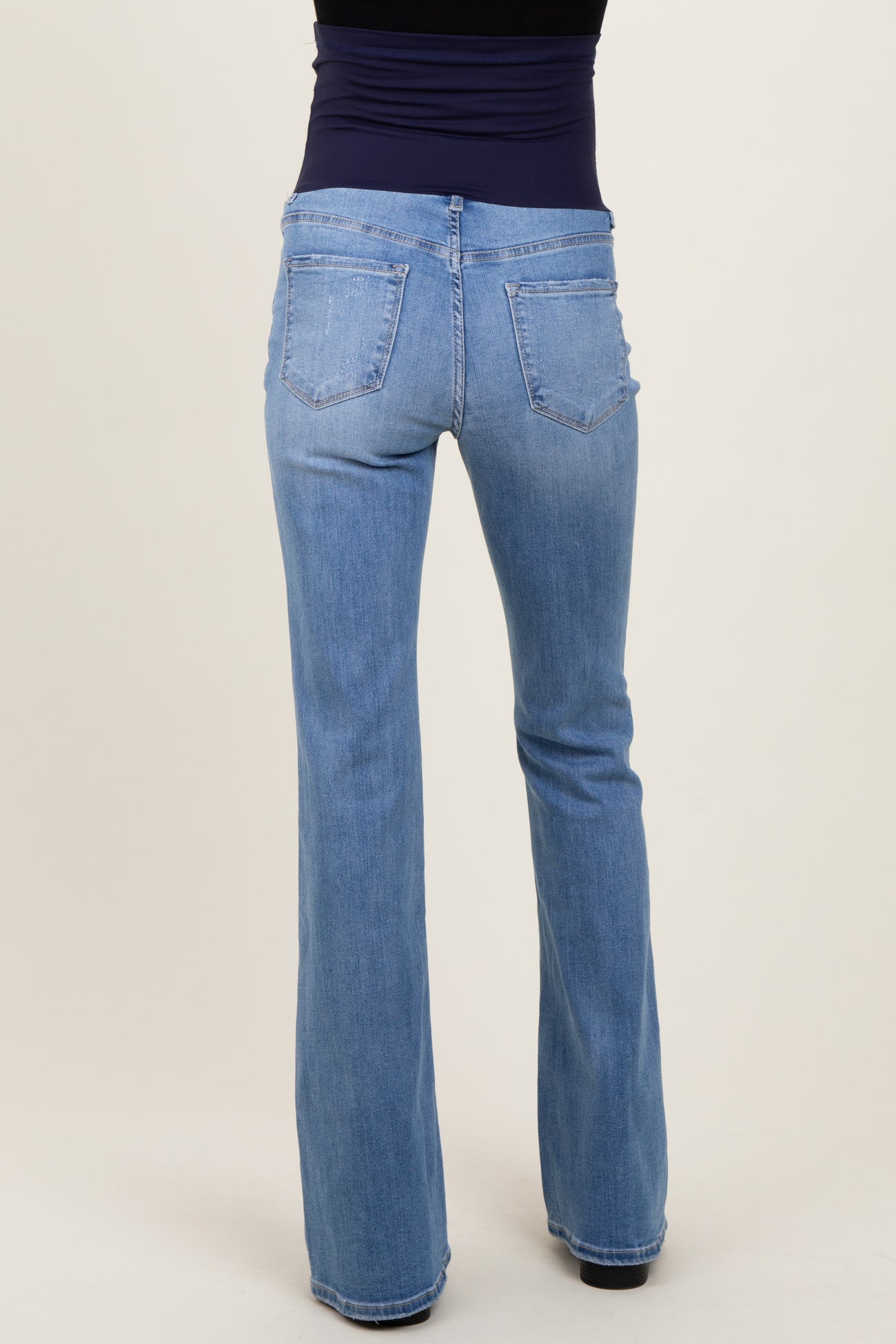 woman wearing light blue maternity flared jeans viewed from the back, showcasing pockets and a comfortable fit