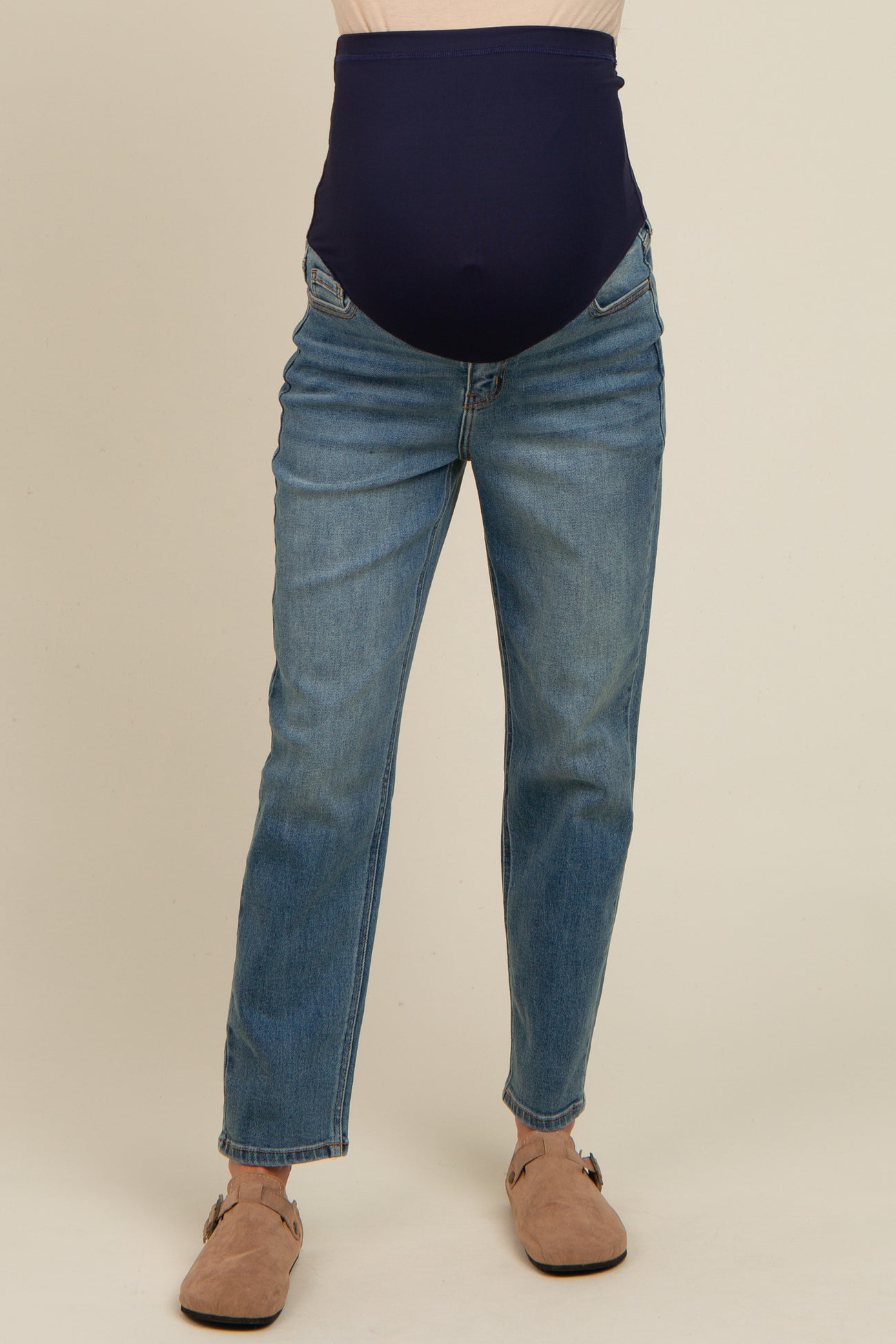 maternity wear dark blue high-waisted jeans with a wide belly band, worn with light brown sandals