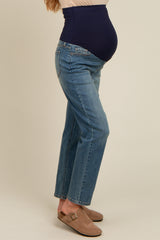 woman wearing blue maternity jeans with a dark blue over-the-bump panel and a visible baby bump