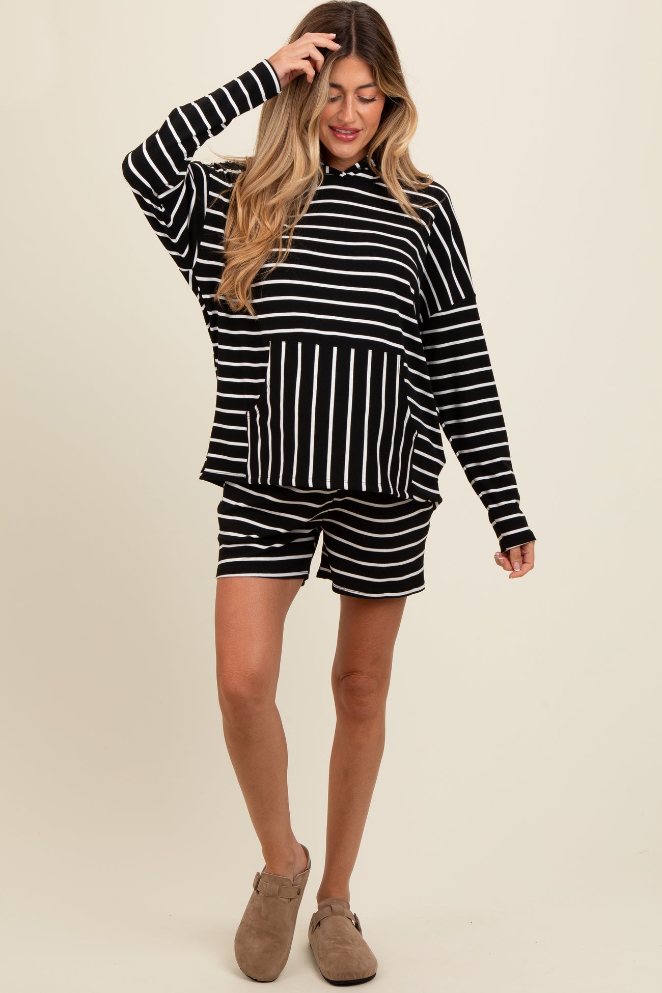 woman wearing a black and white striped maternity hoodie and matching shorts, showing a baby bump