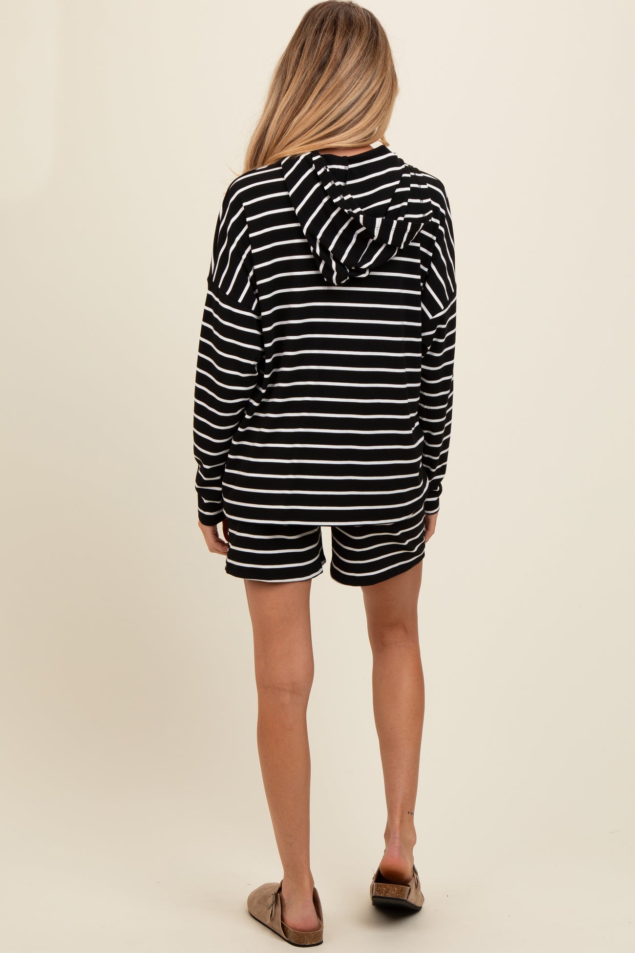 woman wearing a black and white striped maternity hoodie and matching shorts, showing a relaxed fit from the back