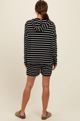 woman wearing a black and white striped hoodie and matching shorts, standing with her back to the camera