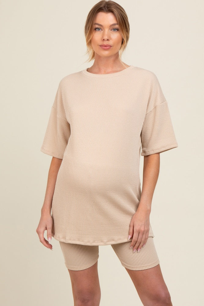 woman wearing a beige maternity oversized t-shirt dress with matching bike shorts, showing a visible baby bump