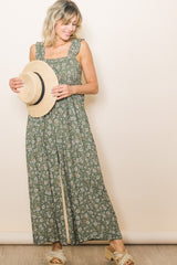 woman wearing a green floral maxi dress with square neckline and holding a straw hat
