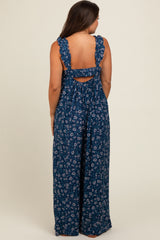 woman wearing a navy blue floral maternity jumpsuit with ruffled straps and a back cutout