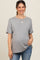 woman wearing a grey short sleeve maternity top and holding her baby bump while smiling