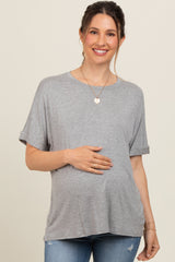 woman wearing a gray short sleeve maternity top and gently holding her baby bump